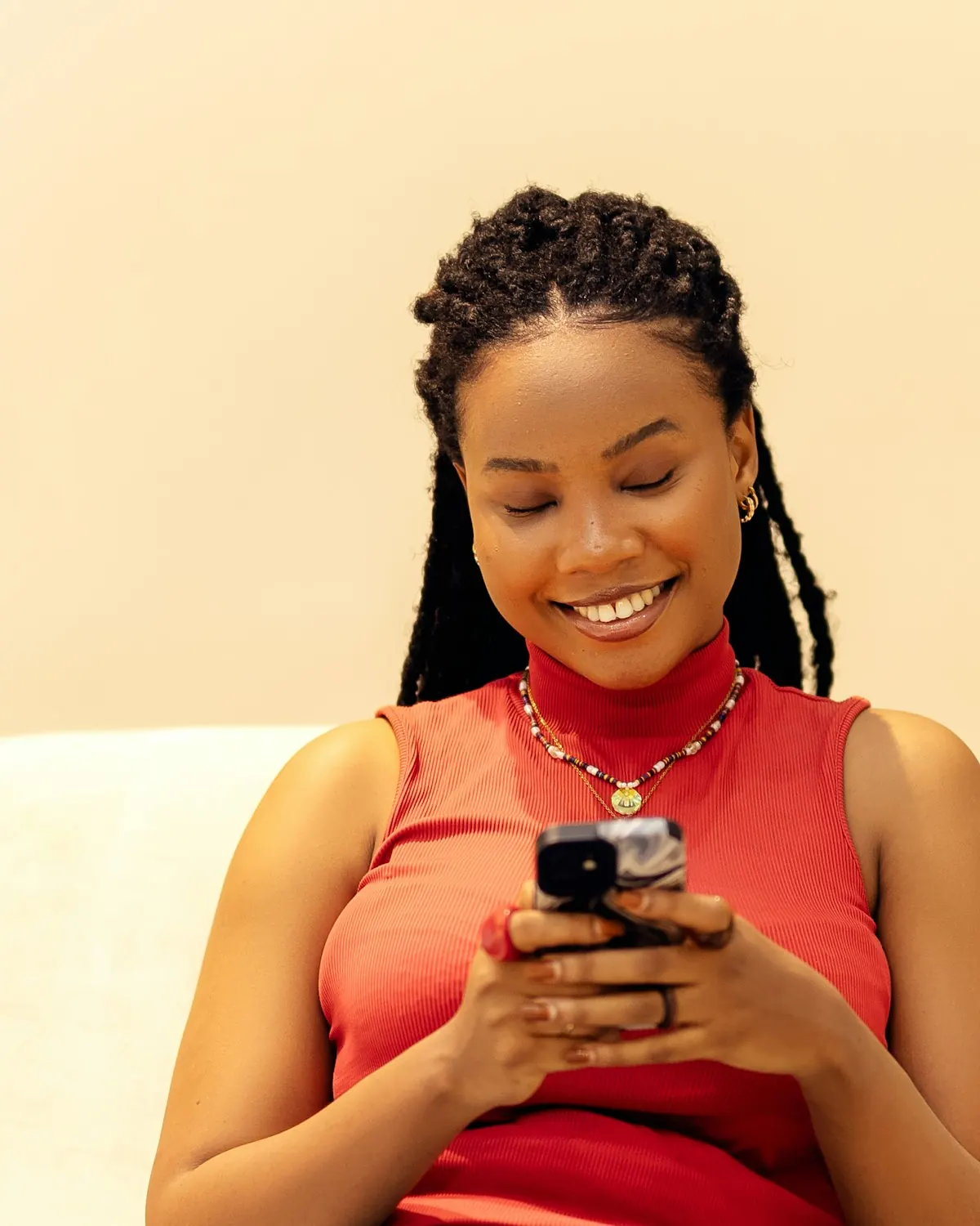 A smiling woman sitting on a sofa at home, looking at her phone